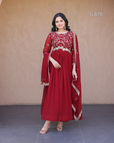 Woman wearing a red traditional outfit with white embroidery against a plain background