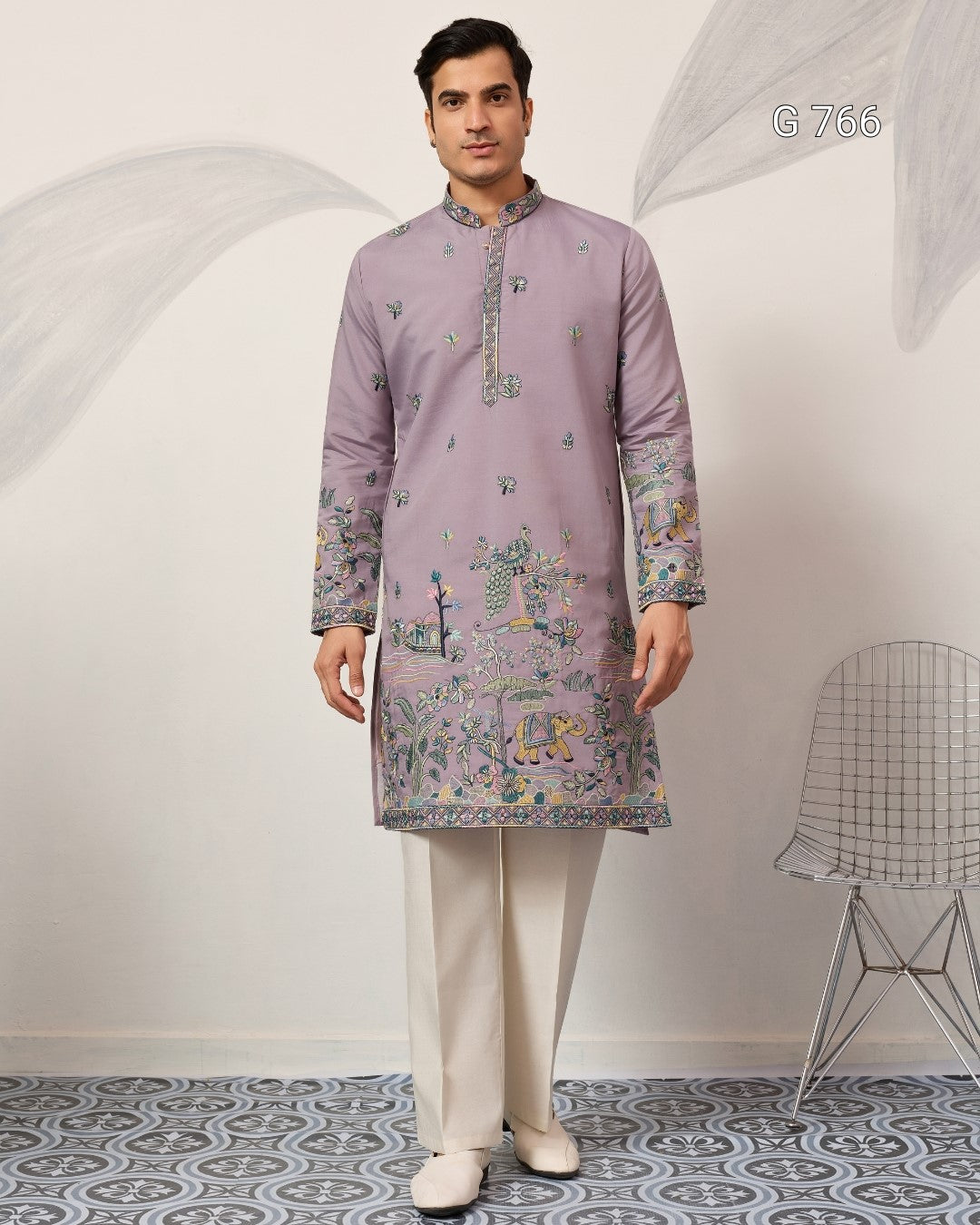 Man wearing a patterned kurta with white pants in a minimalistic room.