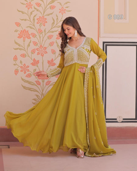 Woman wearing a yellow traditional outfit with floral wall and pink flowers in the background