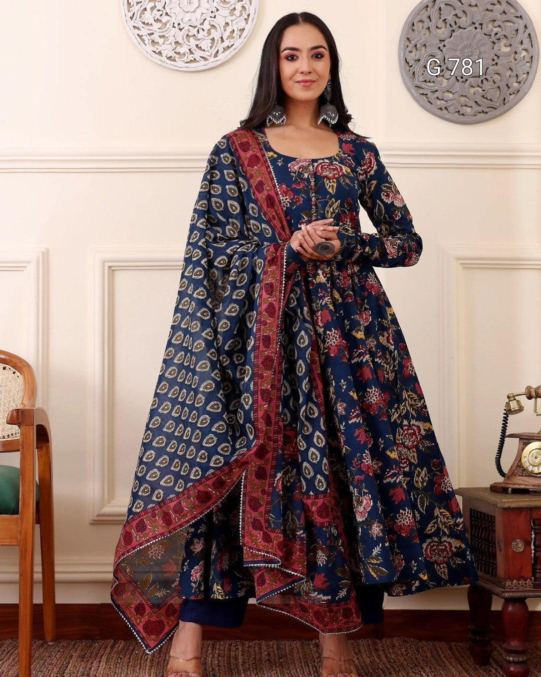 Woman wearing a traditional blue and red patterned outfit in an elegant room.