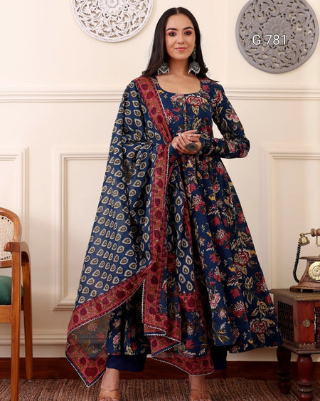 Woman wearing a traditional blue and red patterned outfit in an elegant room.