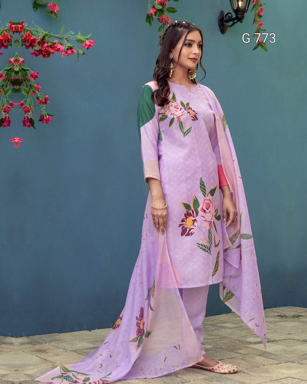 Woman wearing a lavender outfit with floral embroidery against a blue wall.
