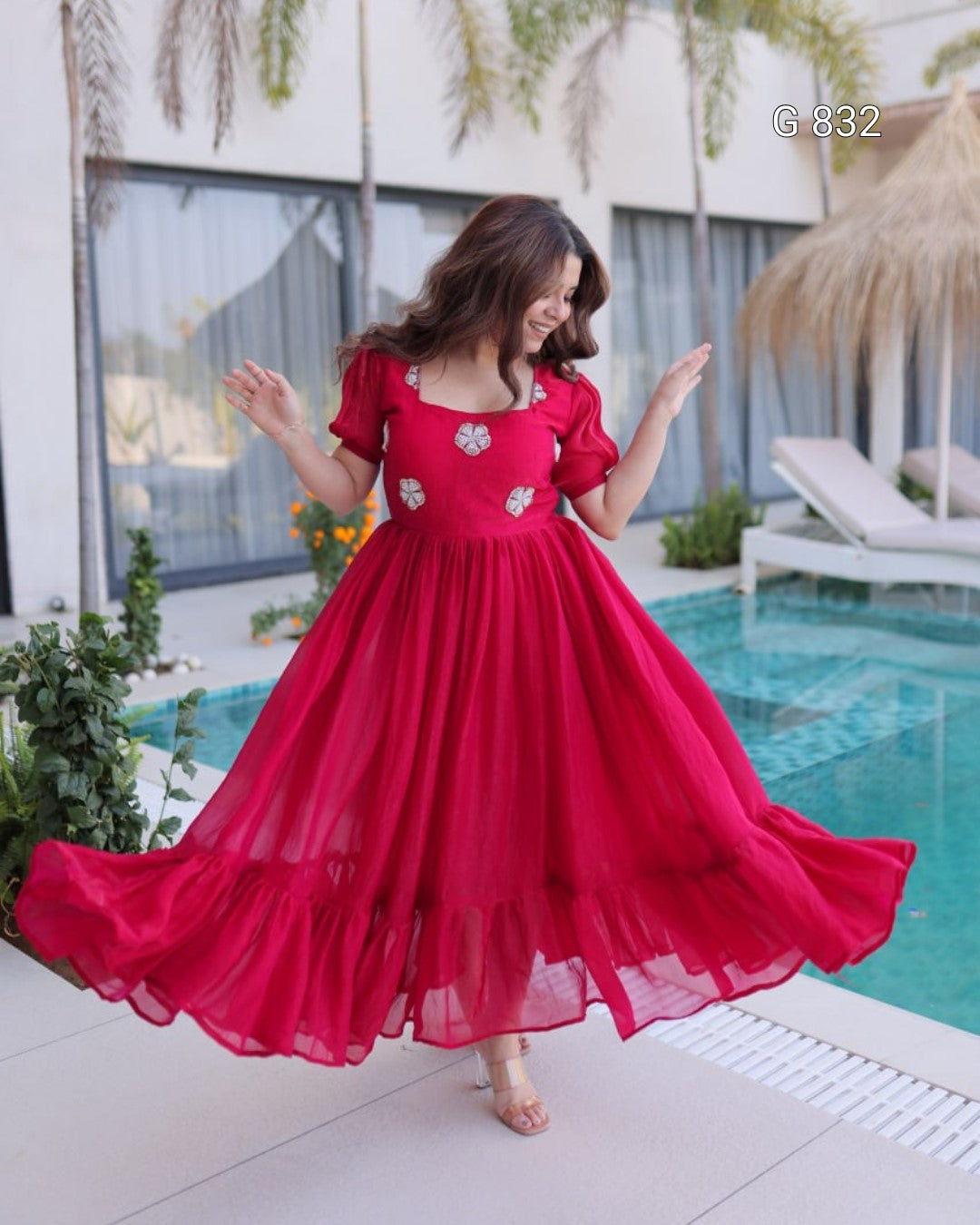Woman in a red dress standing by a pool with a blurred background