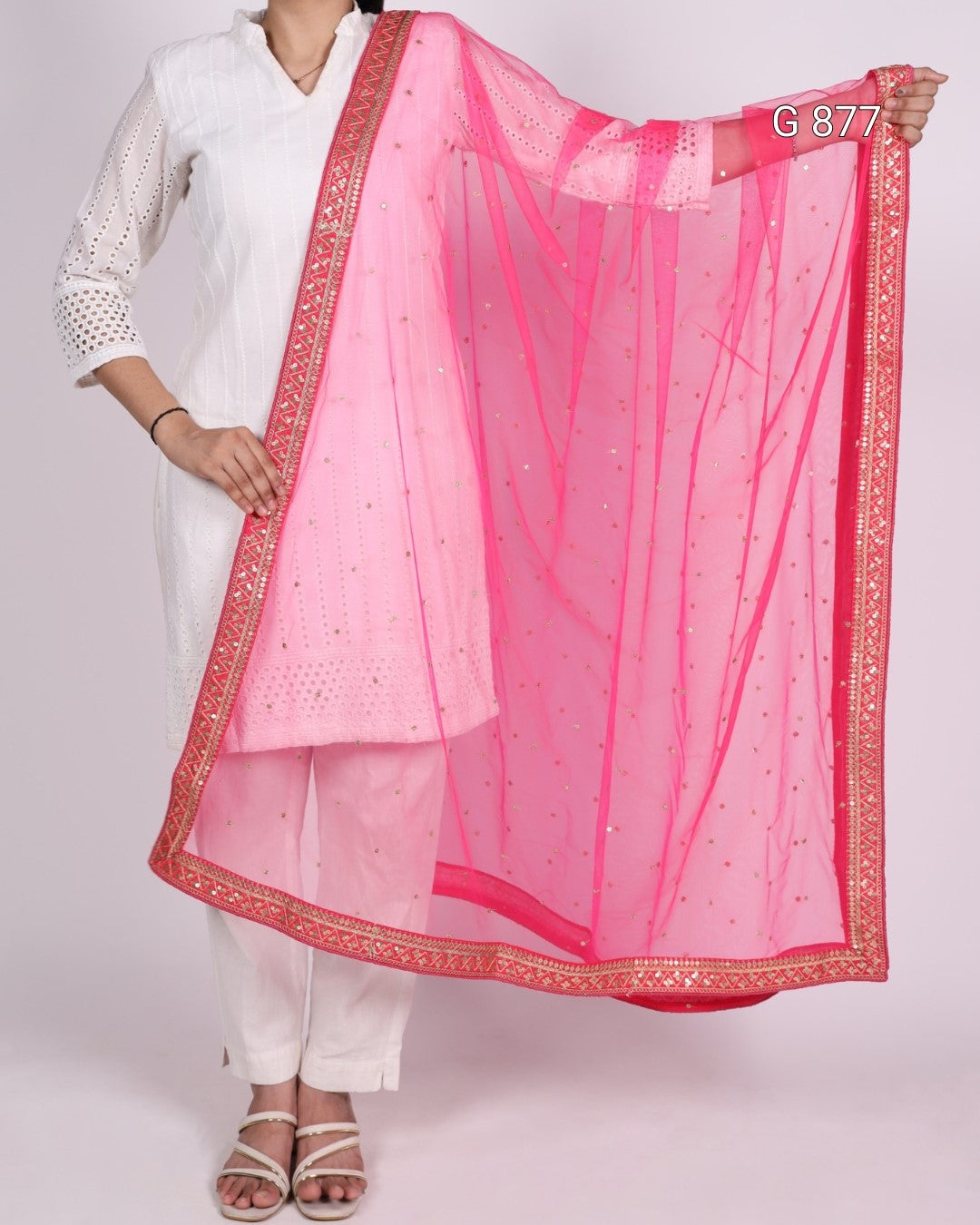 Person wearing a white outfit with a pink dupatta draped over the shoulder on a white background