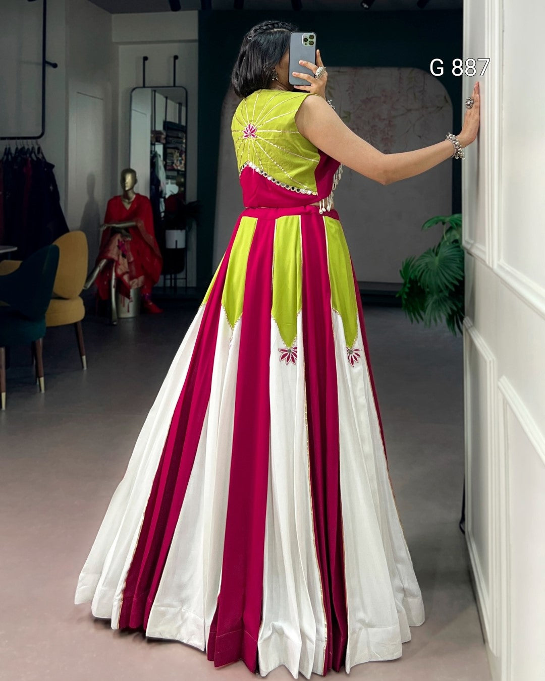 Woman taking a mirror selfie wearing a colorful dress with vertical stripes in a room.