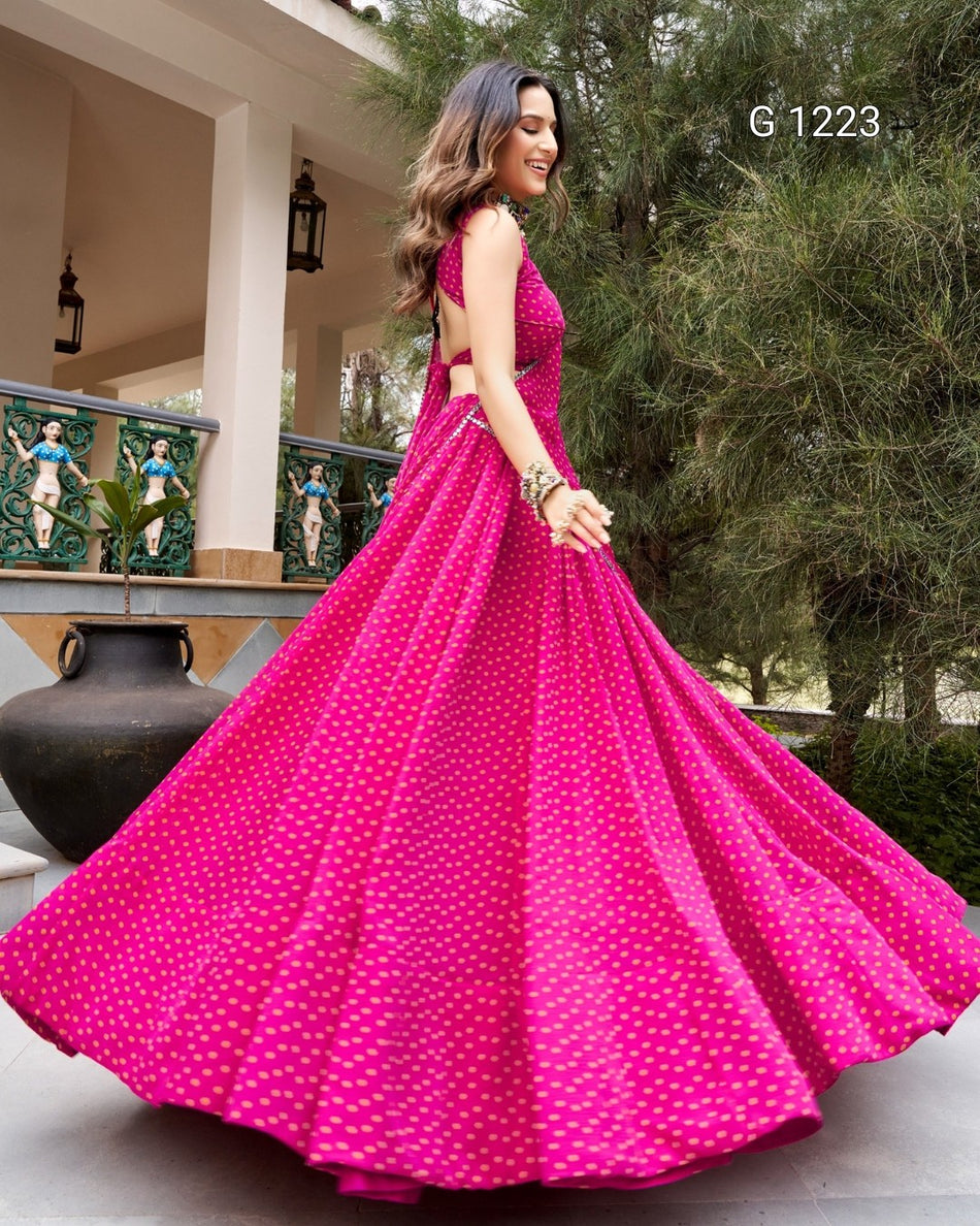 A woman wearing a bright pink sleeveless gown with a small white allover print, captured in a full flowing skirt on an outdoor porch with trees in the background.