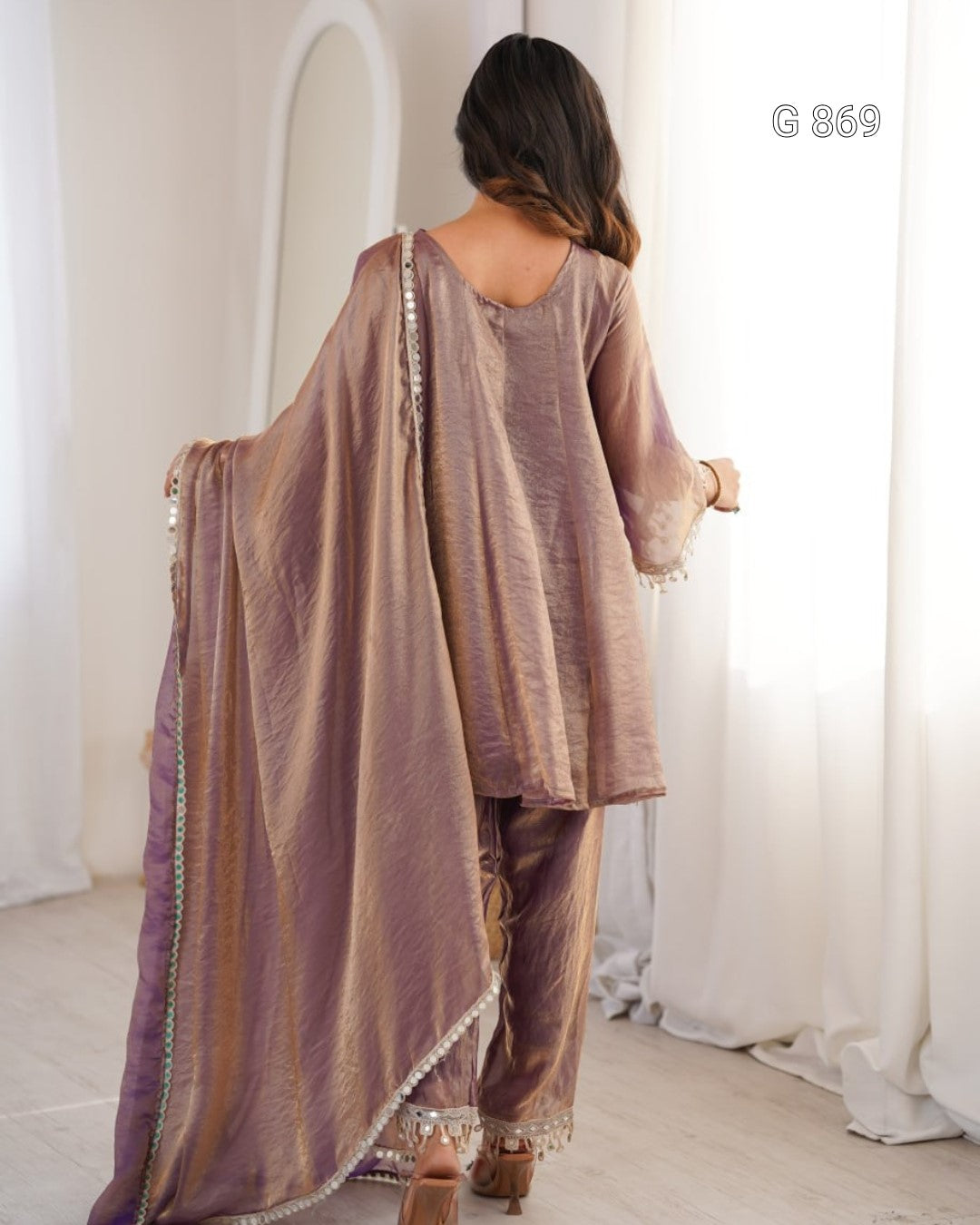 Woman wearing a brown traditional outfit with a dupatta in a minimalistic setting