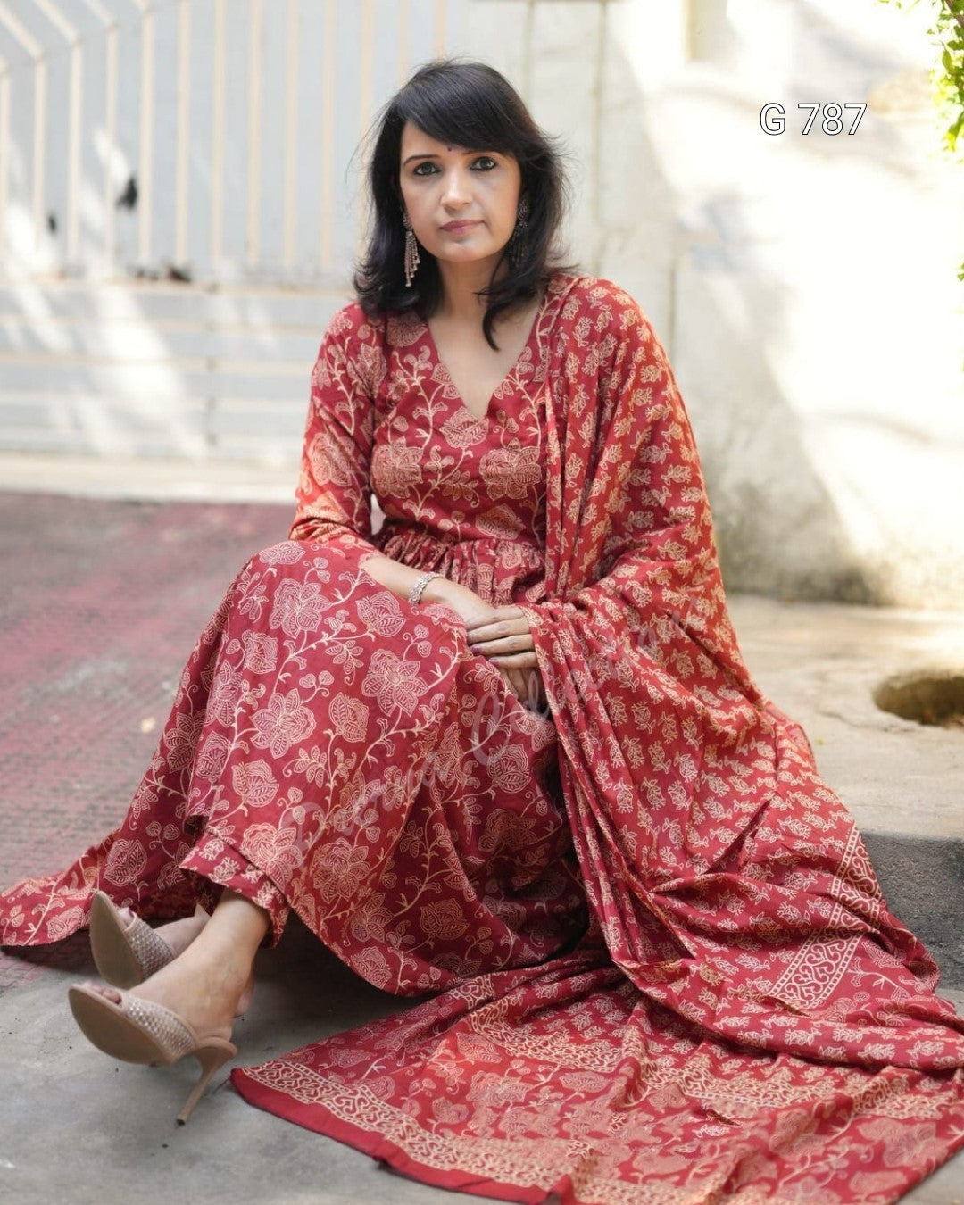 Woman wearing a red patterned dress sitting outdoors.