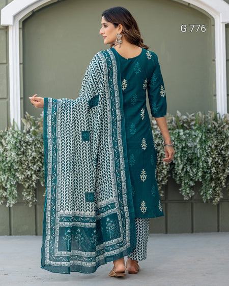 Woman wearing a teal embroidered outfit with a matching dupatta, standing outdoors.