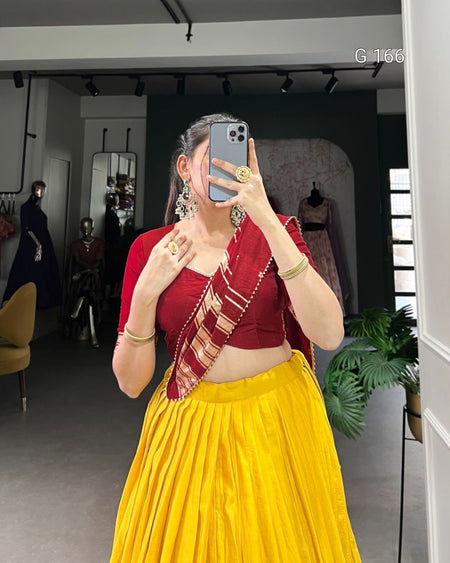 Woman taking a mirror selfie wearing a red blouse and yellow saree in a store setting.