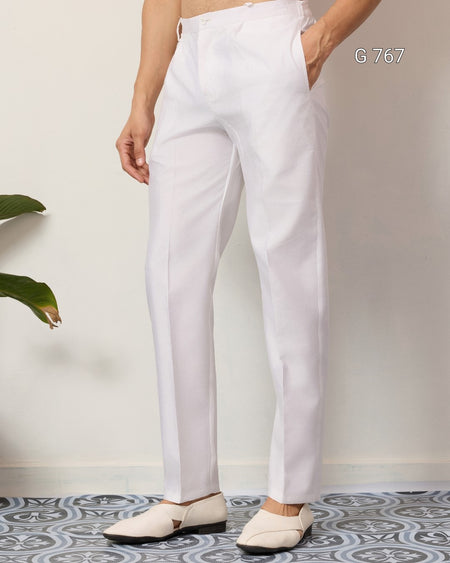 Person wearing white pants standing on a patterned floor with a plant in the corner.