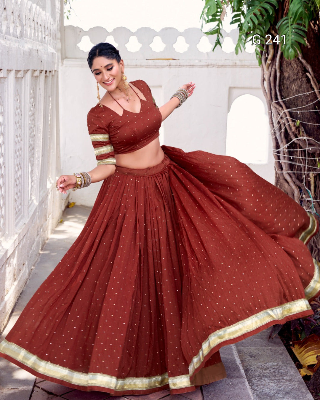Woman in a traditional maroon outfit with gold details dancing outdoors.