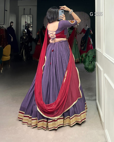 Woman taking a mirror selfie wearing a traditional purple and red saree in a clothing store.