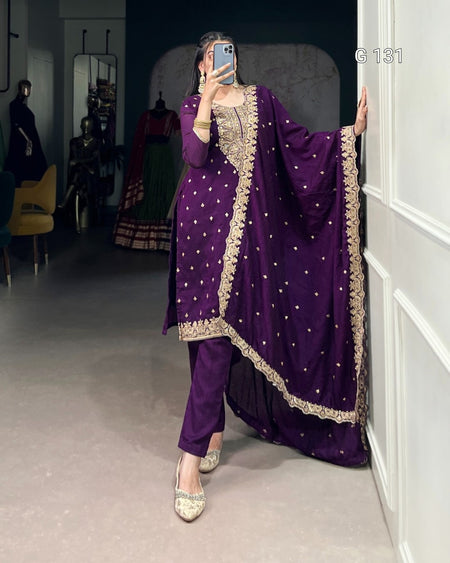 Person wearing a purple traditional outfit with gold detailing in a room.