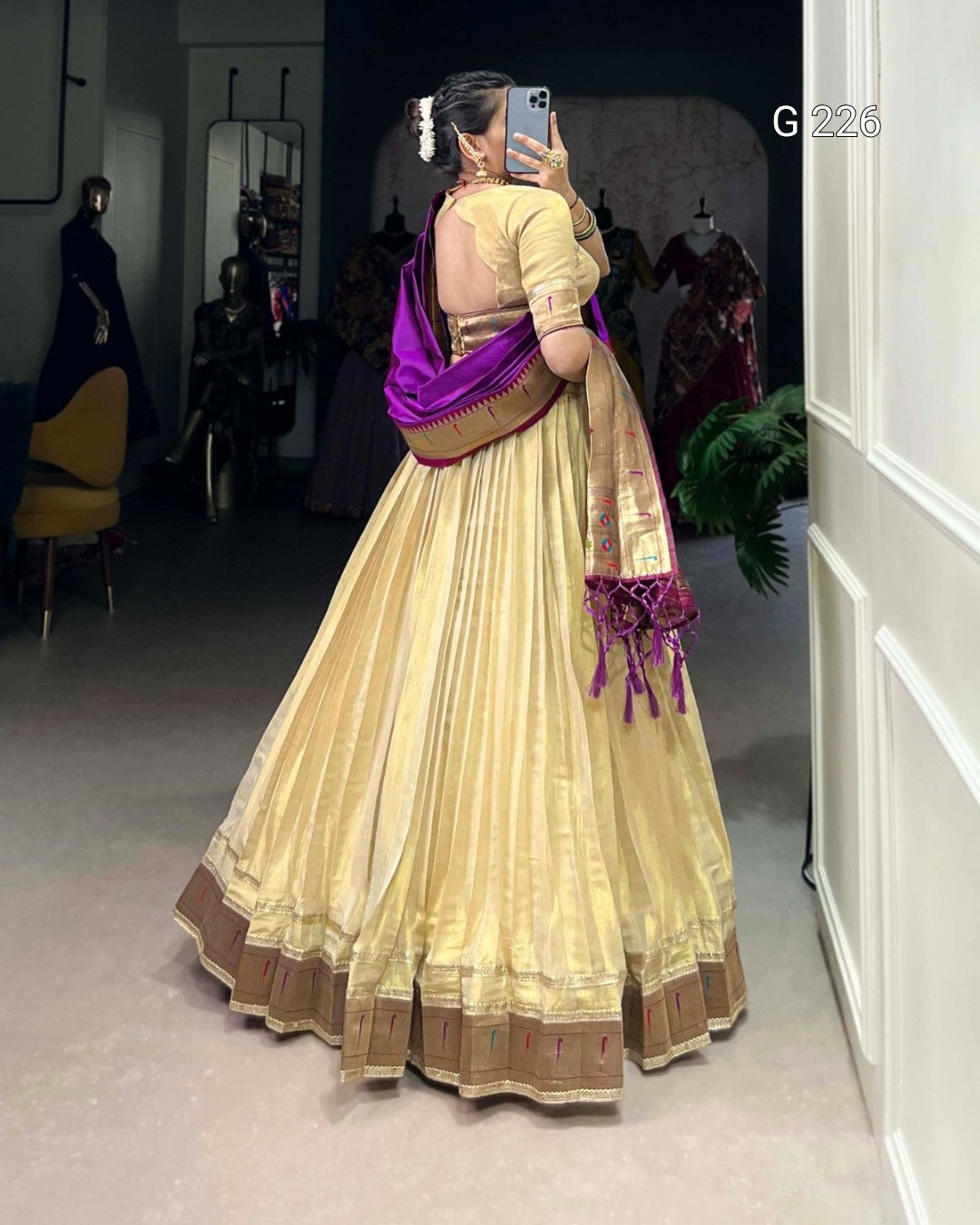 Person wearing a traditional beige and purple saree in a room setting.