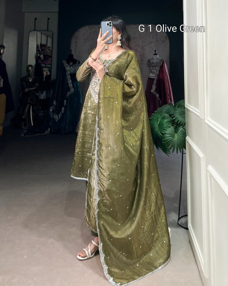 Person wearing a long olive green dress with silver details in a room.