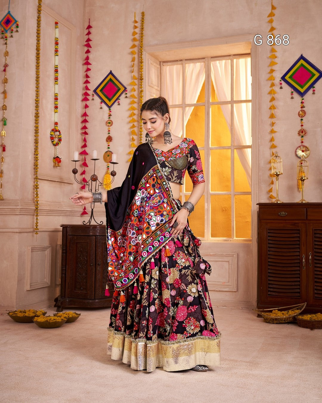 Woman in a colorful traditional outfit standing in a decorated room with hanging decorations.