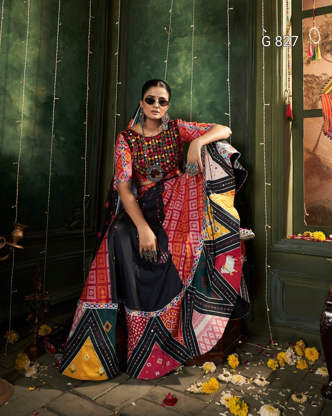 Woman in a colorful traditional outfit standing against a dark green wall with decorative elements.