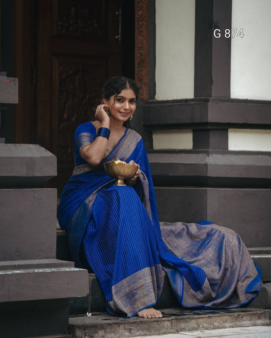 Woman in a blue saree sitting on steps holding a bowl.