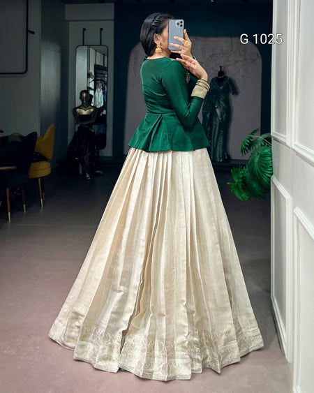 A woman takes a mirror selfie in a boutique wearing a traditional Indian outfit consisting of a dark green velvet peplum top and a voluminous cream-colored silk Anarkali skirt with gold zari embroidery.