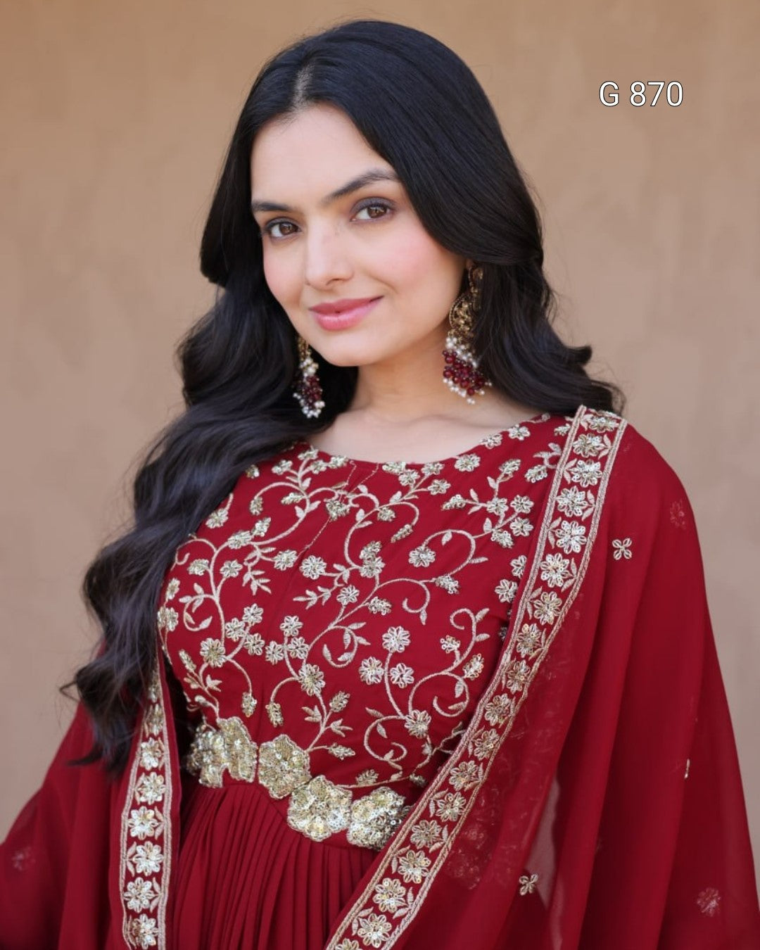 Woman wearing a red embroidered saree against a beige background