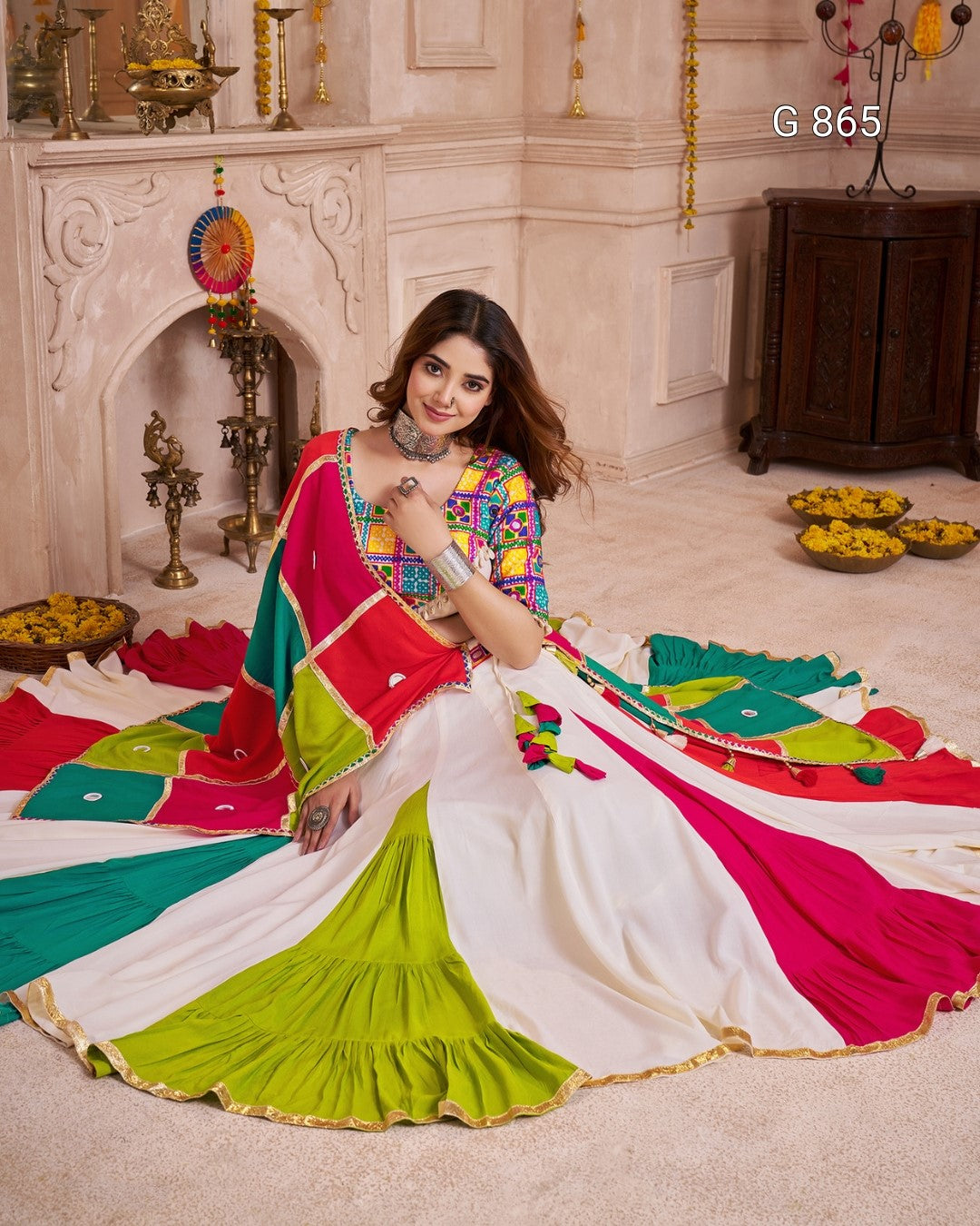 Woman in a colorful saree sitting on the floor with decorative items in the background