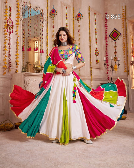 Woman in a colorful traditional outfit with a vibrant saree in a decorated room.