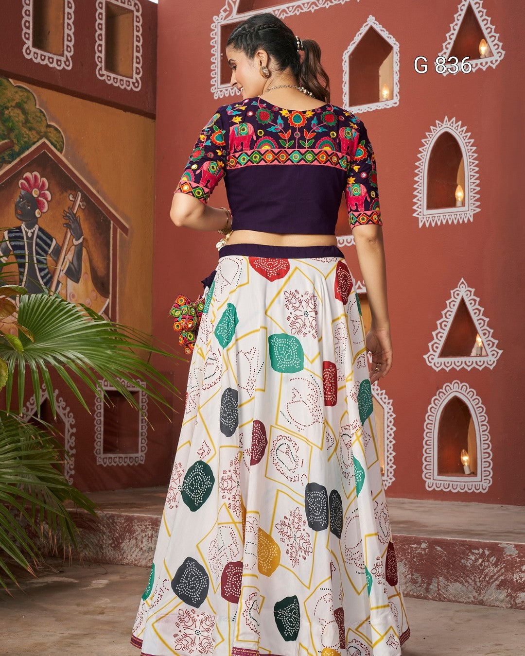 Woman wearing a colorful traditional outfit with a patterned skirt and blouse in a decorative setting.