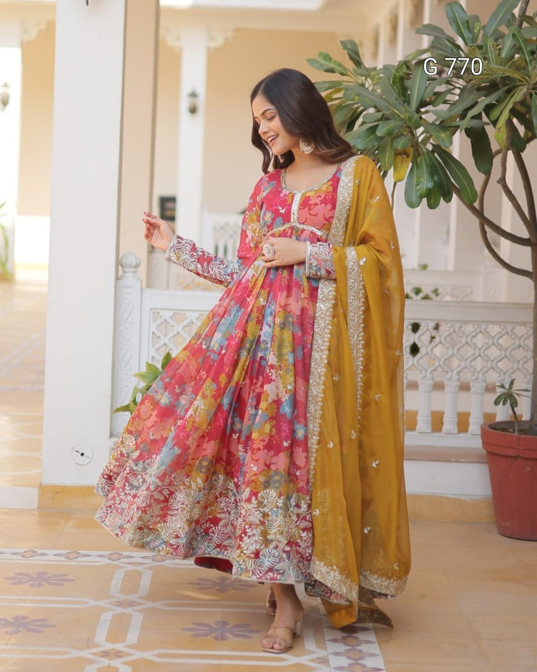 Woman in a colorful traditional outfit standing in a decorated indoor setting.