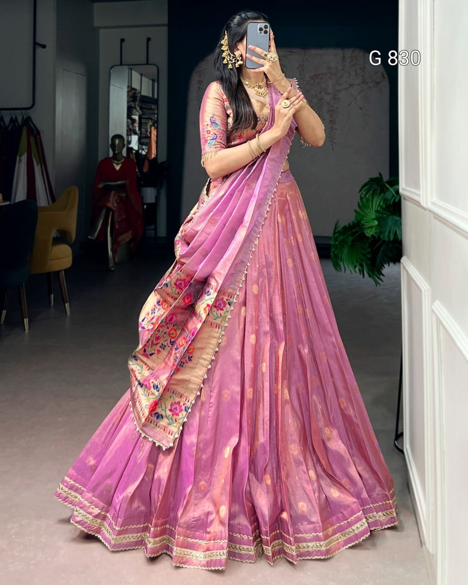 Woman wearing a pink saree with gold details in an indoor setting.