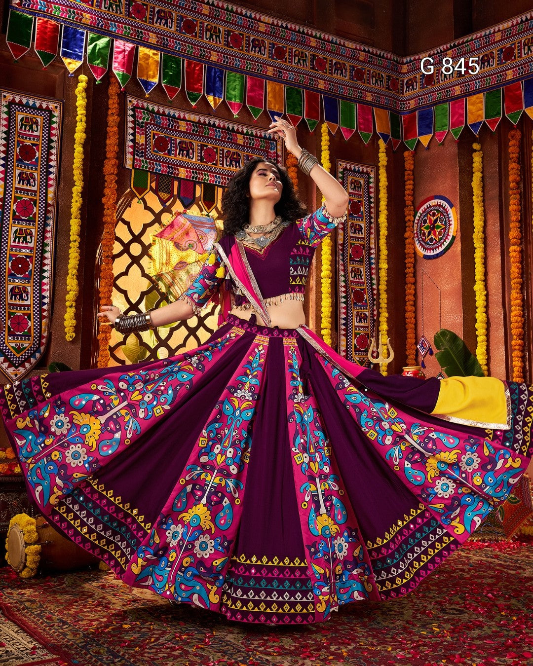 Woman in a traditional purple and colorful outfit with a decorated background