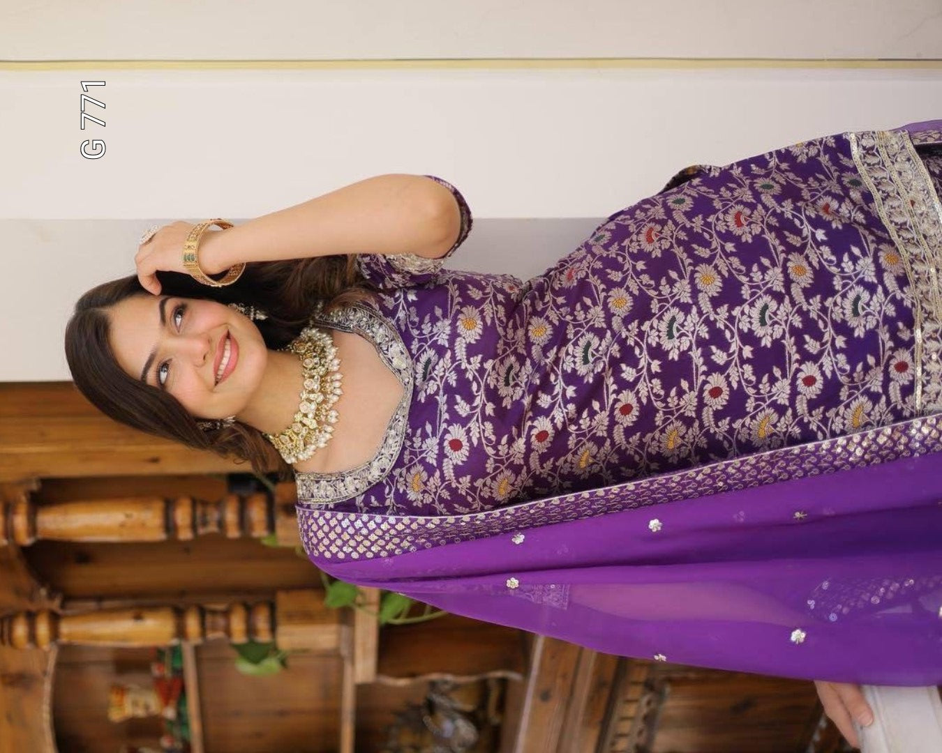 Woman wearing a purple traditional outfit with floral patterns indoors.
