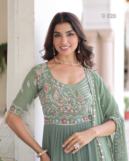 Woman wearing a green embroidered dress with a matching shawl indoors.