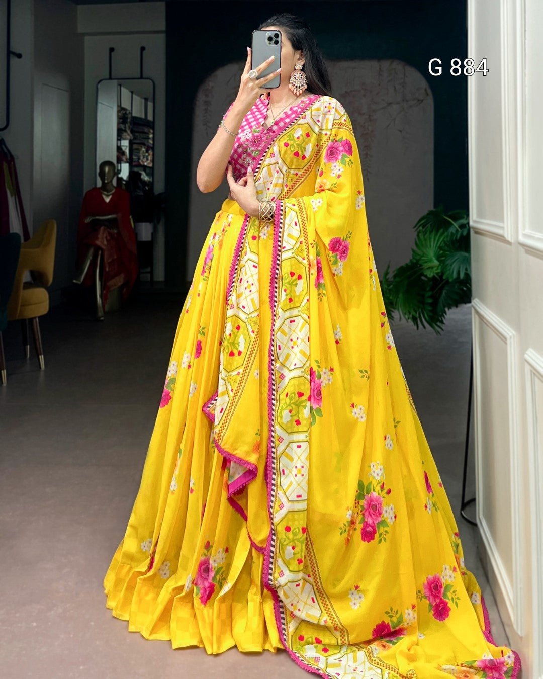 Woman wearing a bright yellow saree with floral patterns indoors.