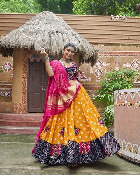 Woman in traditional Indian attire standing in front of a decorative hut.