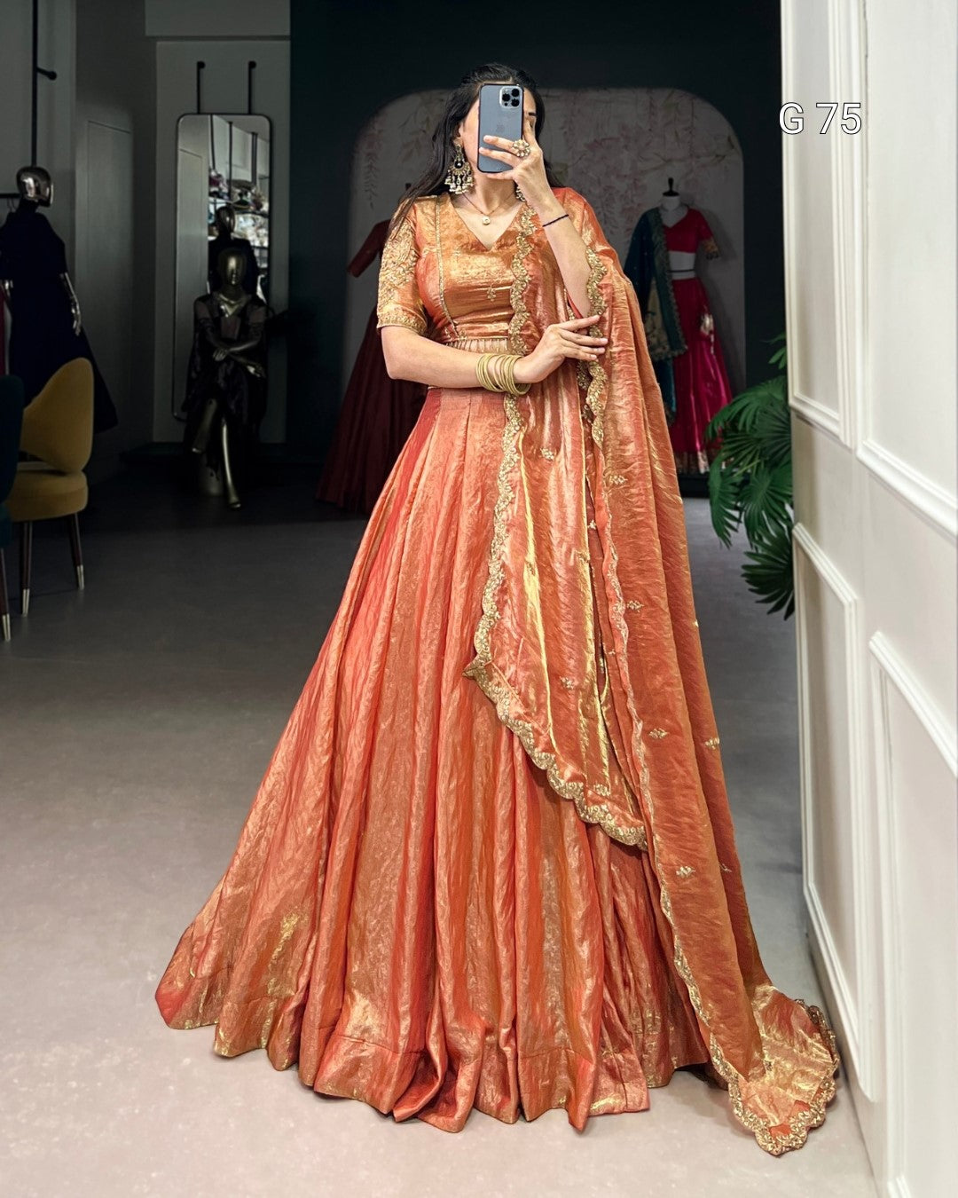 Person wearing a traditional peach-colored outfit with gold details in a room.