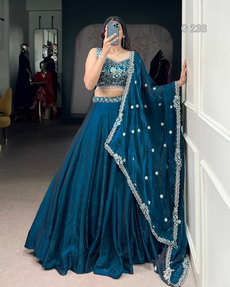 Person wearing a blue traditional outfit with a matching dupatta in a room.