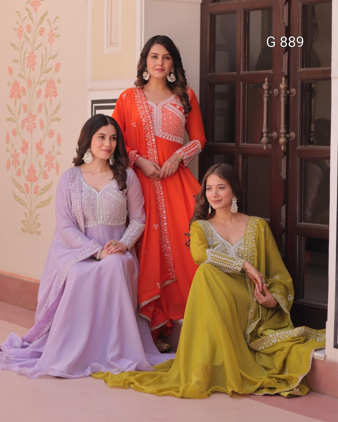 Three women in traditional outfits posing indoors with decorative elements.