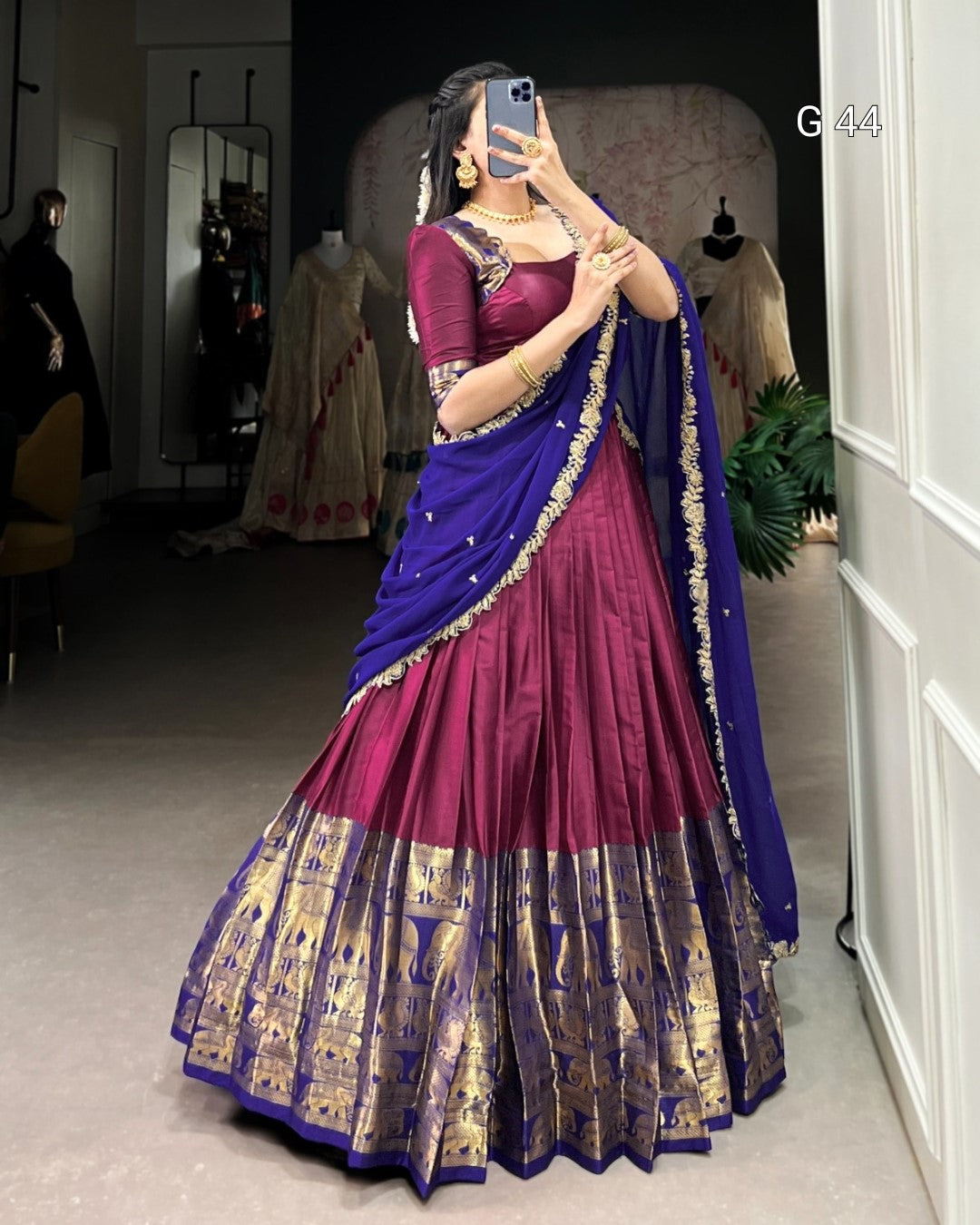 Woman wearing a traditional purple and blue saree with gold patterns in a room.