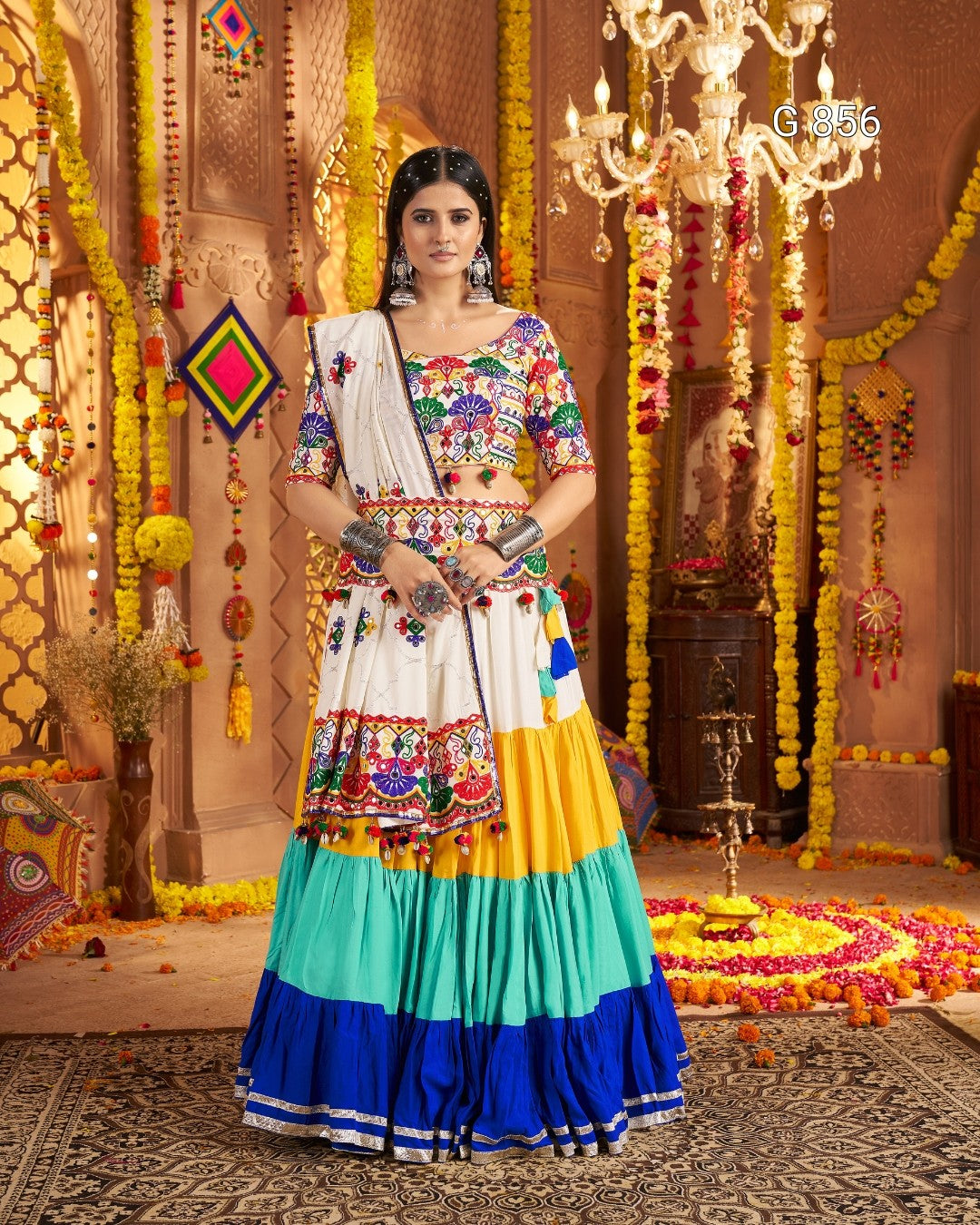 Woman in a colorful traditional outfit standing in a decorated indoor setting.
