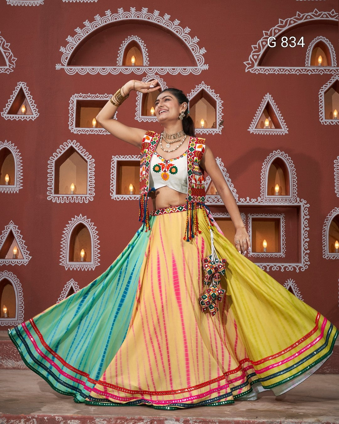 Woman in a colorful traditional outfit dancing in front of a decorative wall.