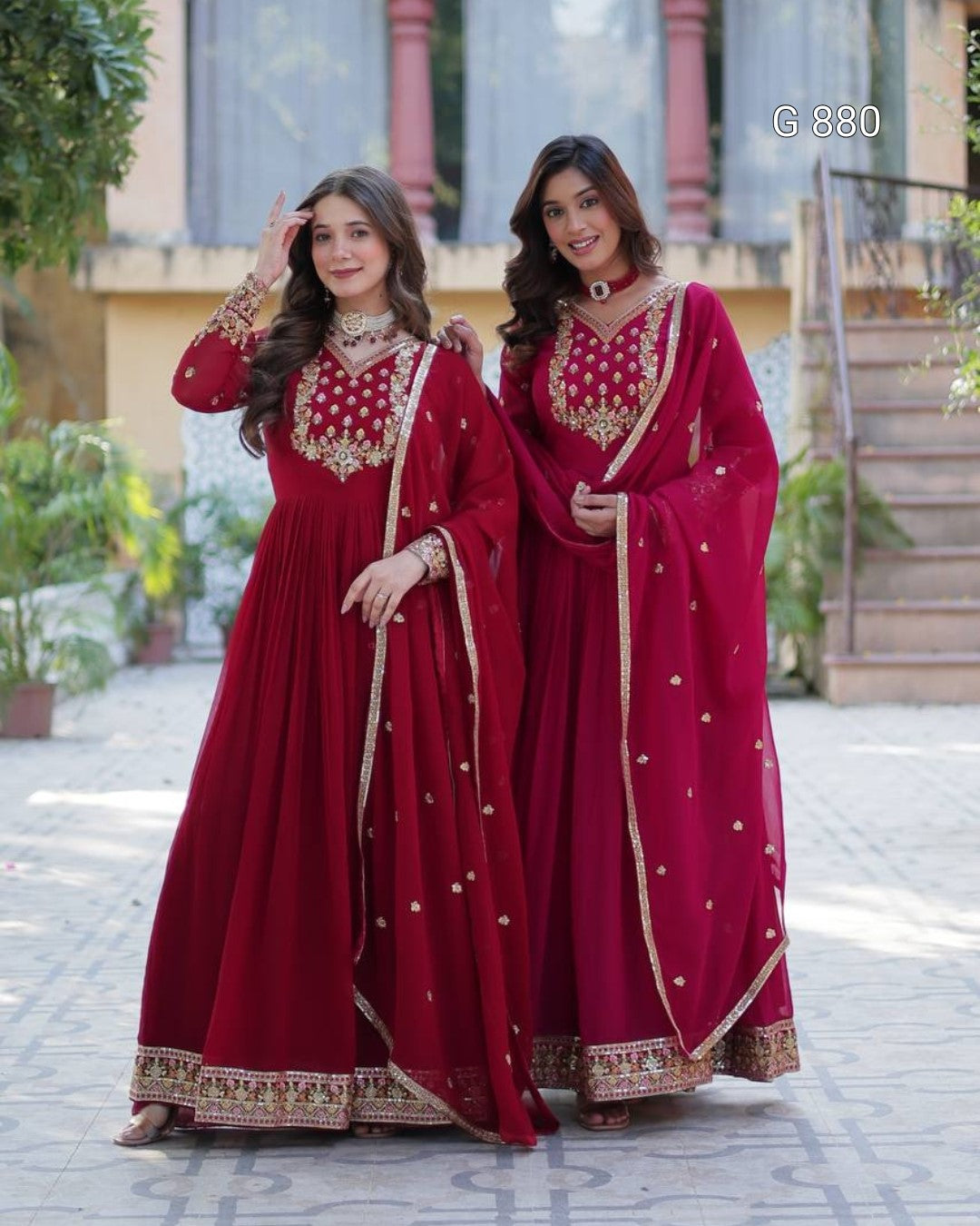 Two women in red traditional outfits standing outdoors.