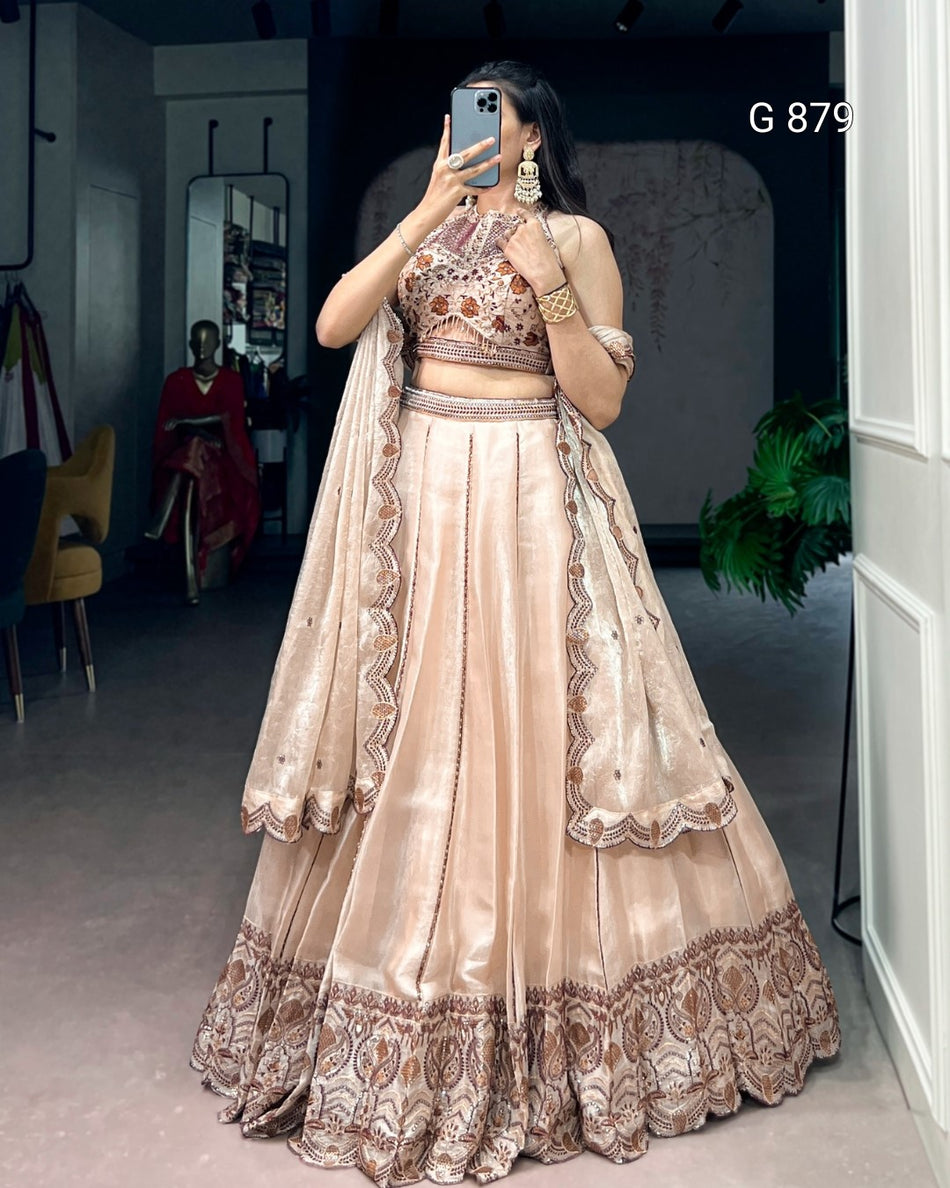 Woman wearing a beige and brown embroidered lehenga in a room.