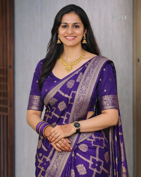 Woman wearing a purple saree with gold patterns against a neutral background