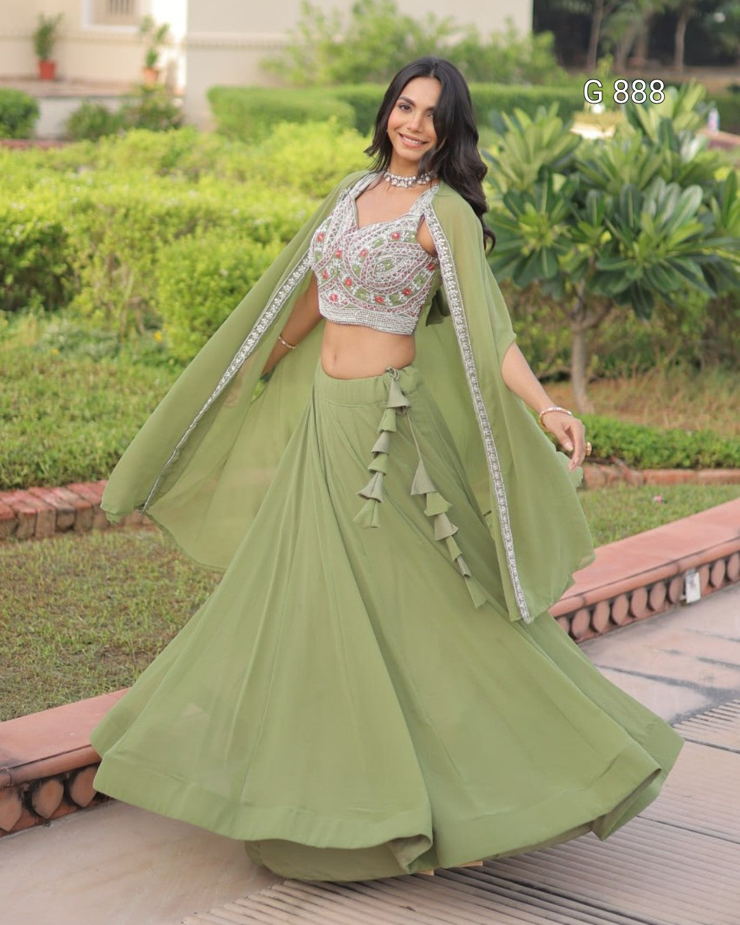 Woman in a green traditional outfit with a cape standing outdoors.
