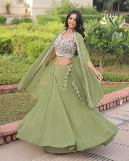 Woman in a green traditional outfit with a cape standing outdoors.