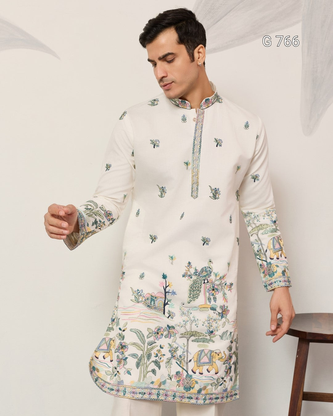Man wearing a white embroidered kurta with intricate patterns on a plain background