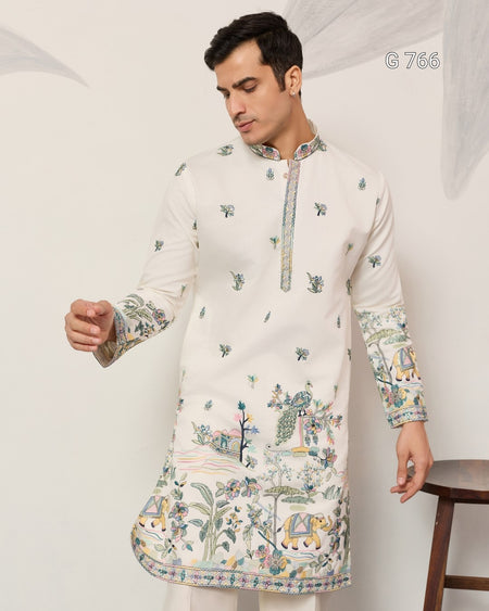 Man wearing a white embroidered kurta with intricate patterns on a plain background