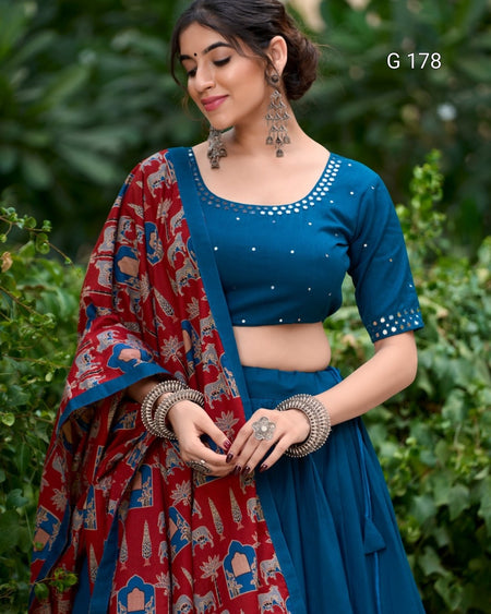 Woman wearing a blue blouse and red patterned dupatta against a green leafy background