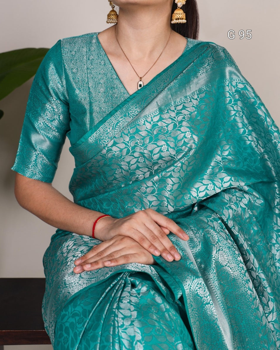 Teal saree with white floral patterns worn by a person, against a neutral background.